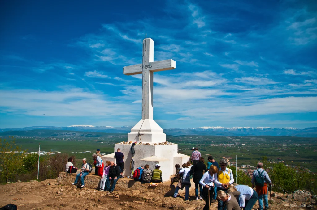 Hodočasnici okupljeni u molitvi oko križa u Međugorju, svetom mjestu za razmišljanje i pobožnost